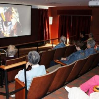 A small audience watching a movie in a cozy theater setting.