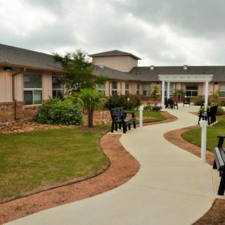 A well-maintained garden area with a winding pathway and benches outside a building.
