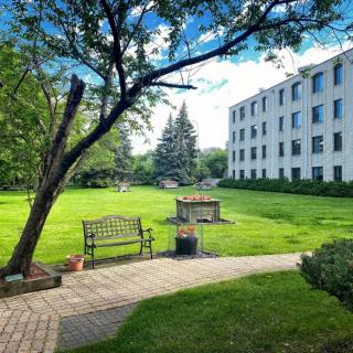 A peaceful park area with benches and a paved pathway next to a multi-story building.