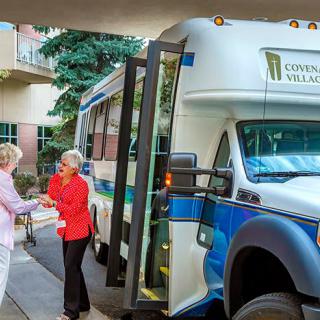Two people interacting near a community shuttle bus.