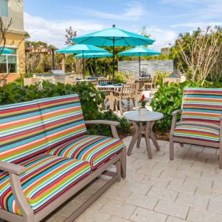 A cozy outdoor patio with colorful striped seating and umbrellas, perfect for relaxation.