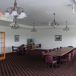 A spacious conference room with a long table, several chairs, and elegant chandeliers.