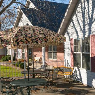 A cozy outdoor patio area with a table, chairs, and an umbrella in front of a house.