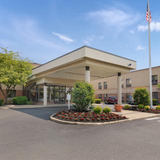 Welcoming entrance of a commercial building with landscaped surroundings and an American flag.