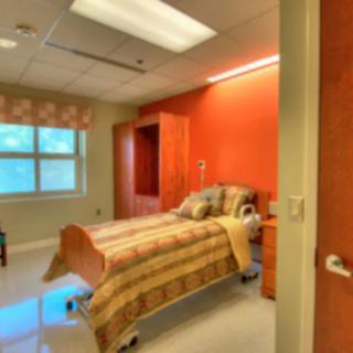 A cozy hospital room with a single bed and warm lighting.