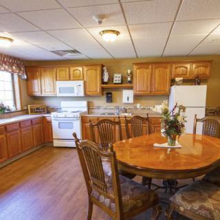 A cozy kitchen with wooden cabinets, a round dining table, and essential appliances.