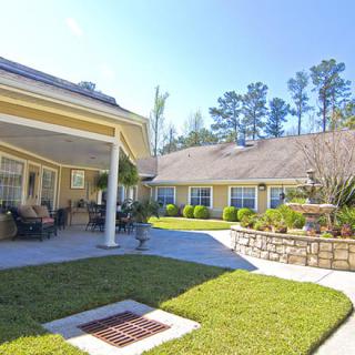 A sunny residential courtyard featuring well-maintained landscaping and a patio area.