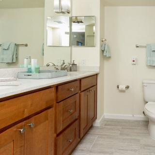 A clean and modern bathroom with a wooden vanity, large mirror, and neatly arranged towels.