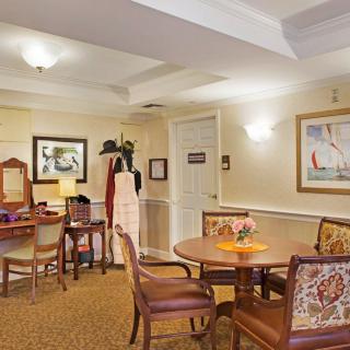 A cozy dining area with multiple tables and chairs, warmly lit and decorated with artwork on the walls.