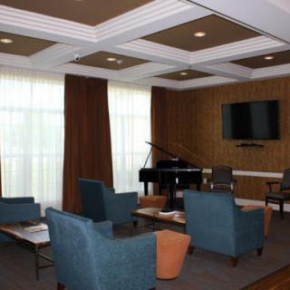 A stylish living room featuring modern furniture, a grand piano, and ample natural light.