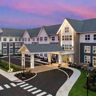 A modern residential building with a welcoming entrance under a vibrant sunset sky.