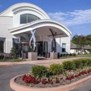 A modern building entrance with landscaped flower beds under a clear blue sky.