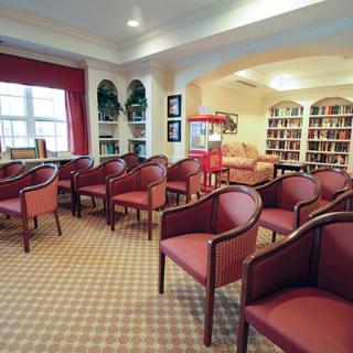 A cozy library room with rows of red chairs and bookshelves lining the walls.