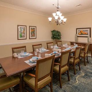A well-appointed dining room with a long table set for a meal, surrounded by chairs and illuminated by a chandelier.