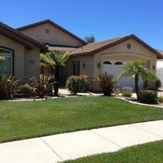 A suburban house with a well-maintained lawn and palm trees.