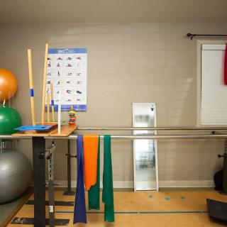 A physical therapy room equipped with exercise balls, resistance bands, and various rehabilitation tools.