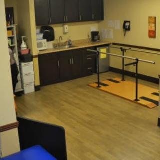 A physical therapy room with parallel bars and medical equipment.