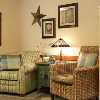 A cozy living room setup featuring two distinct chairs, a decorative lamp, and wall art.