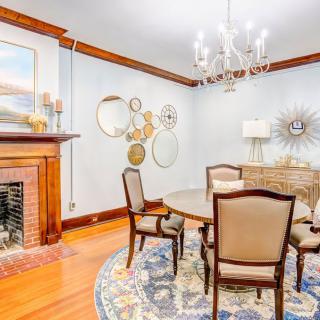 A cozy dining room featuring a round table and chairs, decorated with a chandelier and surrounded by decorative mirrors and a fireplace.