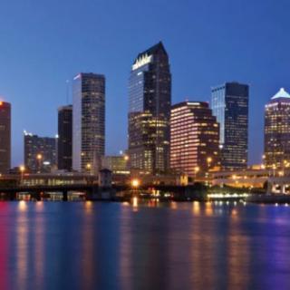 A vibrant city skyline illuminated at night, reflecting on calm waters.