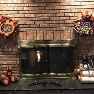 A cozy brick fireplace adorned with Halloween-themed decorations, including pumpkins and festive wreaths.