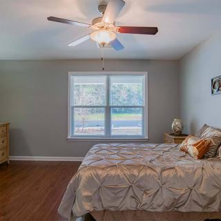 A cozy bedroom with a large bed, ceiling fan, and window allowing natural light to fill the room.