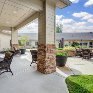 A cozy patio area with outdoor seating and brick columns, offering a serene garden view.