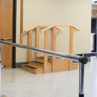 A rehabilitation room featuring parallel bars and a wooden staircase used for physical therapy exercises.