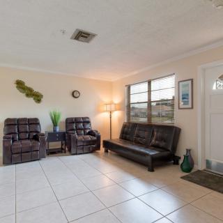 A cozy living room with a sofa, two chairs, a lamp, and tile flooring.