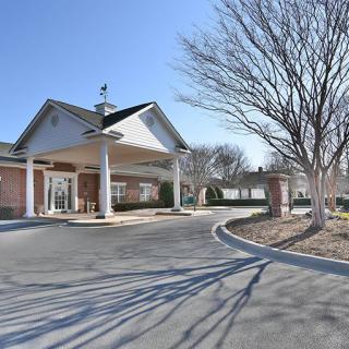 A view of a building entrance with a circular driveway surrounded by trees.