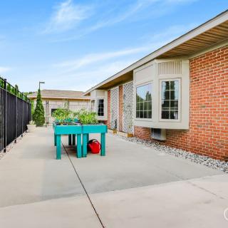 A spacious patio with a garden table and plants next to a brick building.