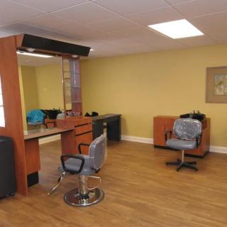 A well-lit hair salon with wooden floors and modern styling stations.