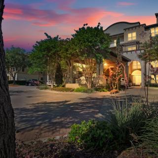 A picturesque view of a building at sunset, with warm lights and surrounding trees.