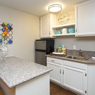 A compact kitchen area featuring white cabinets, a granite countertop, and modern decor.