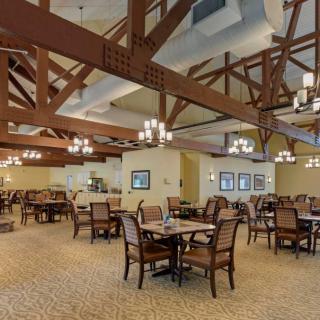 A spacious restaurant dining area with elegant chandeliers and wooden beams.