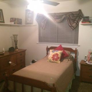 A cozy bedroom with a single bed, wooden furniture, and decorative pillows.