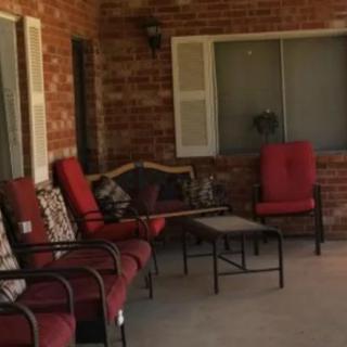 A cozy outdoor patio area with red cushioned chairs and a small table against a brick wall.