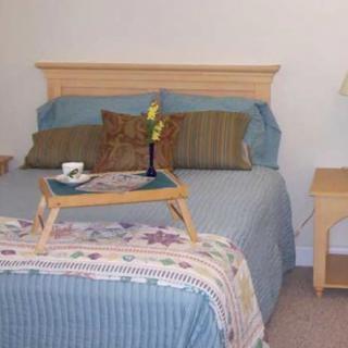 A cozy bedroom with a neatly made bed, adorned with pillows and a breakfast tray on top.