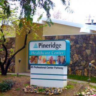 Signage for Pineridge Healthcare Center with surrounding greenery.