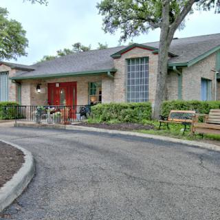 A cozy building with red doors, surrounded by greenery and benches.