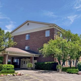 A brick hotel building surrounded by trees with a clear blue sky.