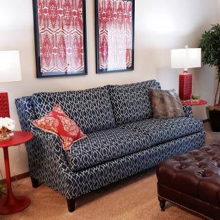 A well-furnished living room featuring a patterned sofa, two matching lamps, and vibrant artwork on the wall.