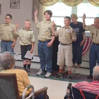 A group of Boy Scouts participating in a ceremony while an audience watches.