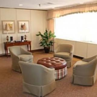 A cozy living room with four chairs arranged around a central table, complemented by artwork and a potted plant.