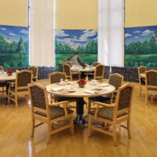 A well-arranged dining room featuring round tables and chairs, with a decorative mural in the background.