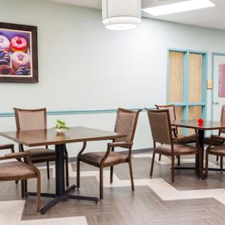 A modern dining area featuring sleek tables and comfortable chairs, complemented by decorative artwork on the wall.