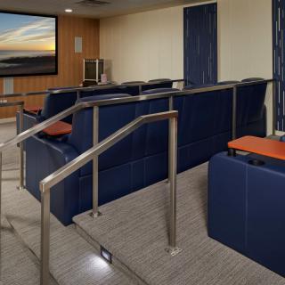 A cozy indoor theater room with tiered seating and a large projector screen.
