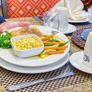 A plate of salmon served with corn and vegetables on a dining table.