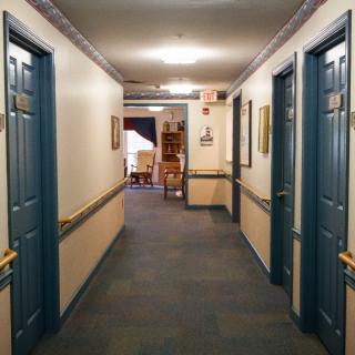 A well-lit hallway with several blue doors, carpeted flooring, and decorative details.
