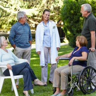 A group of seniors conversing with a doctor in a garden setting.